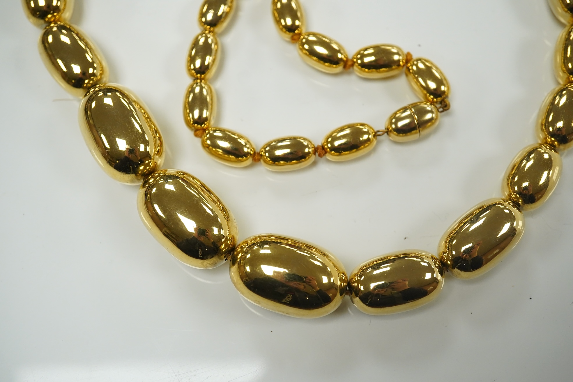 A modern gilt metal graduated oval bead costume necklace, 72cm. Condition - fair to good